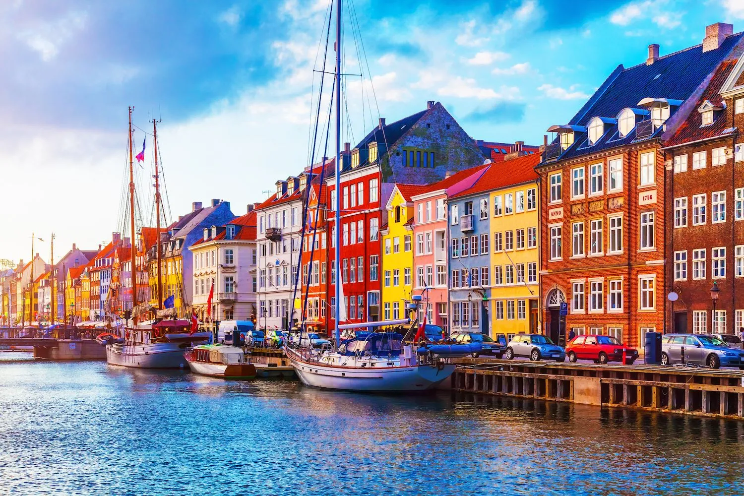 Farverige huse og både langs Nyhavn i København på en solrig dag. Dette ikoniske område er ideelt til en charmerende miniferie på Sjælland, hvor du kan nyde både kultur, historie og afslappende stunder ved vandet i hjertet af hovedstaden.