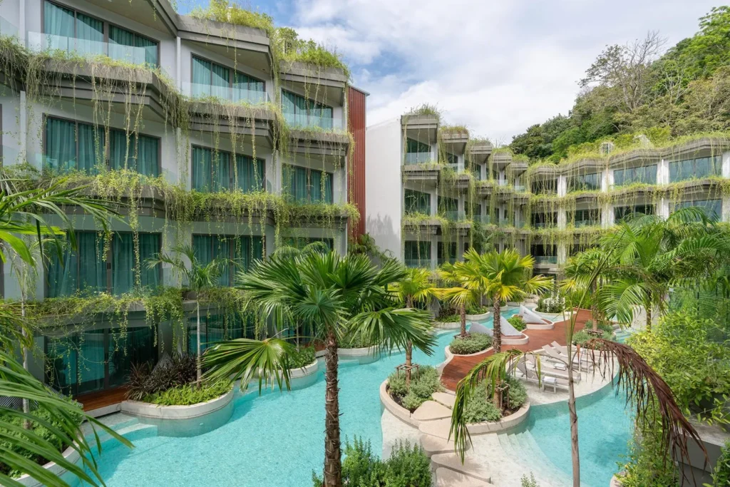 Panwaburi Beachfront Resort set udefra med frodig grøn vegetation, der hænger ned over bygningens altaner og skaber en tropisk og fredfyldt atmosfære ved den indbydende pool.