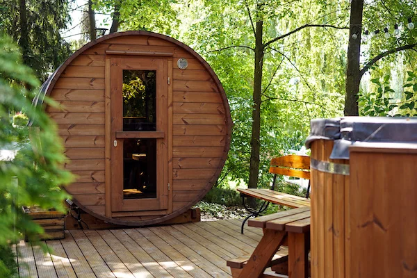 Træ-sauna i unik glamping-stil omgivet af grøn natur, perfekt til afslapning og velvære.